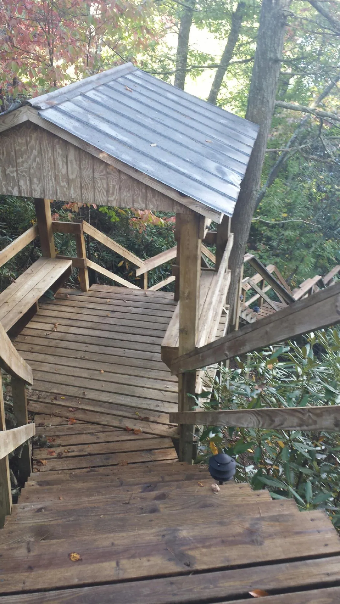 Metal roofed shelter over wooden steps on a wooded walkway in Spring City
