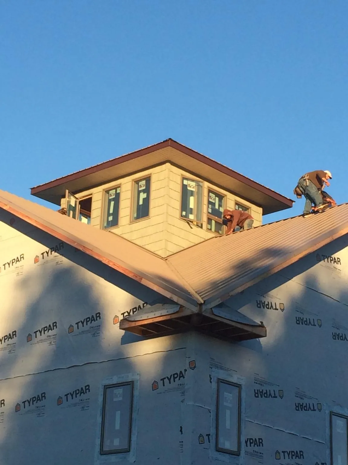 Roofers working around a rooftop cupola on a new metal roof at sunset — Roof Waterproofing in Spring City by Roofing Brothers